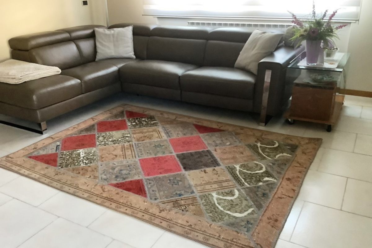 Tappeti salotto Adamello tappeto di Adamello Tappeti posto sotto un divano in pelle nero