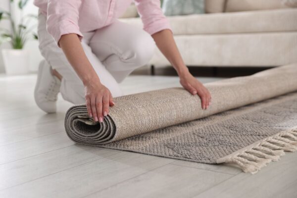 Persona che sta arrotolando un tappeto di colore beige